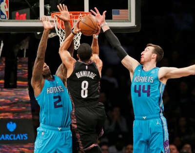 Brooklyn Nets guard Spencer Dinwiddie lifts between two Charlotte Hornets players, Marvin Williams (l) and Frank Kaminsky on the right, during an NBA basketball game at the Barclays Center in Brooklyn, NY on Friday, March 1, 2019, in New York.