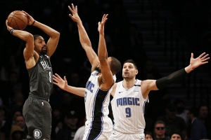 Brooklyn Nets guard, Spencer Dinwiddie, attempting to pass the basketball around Orlando Magic players Isaiah Briscoe (in center) and Nikola Vucevic (on the right)